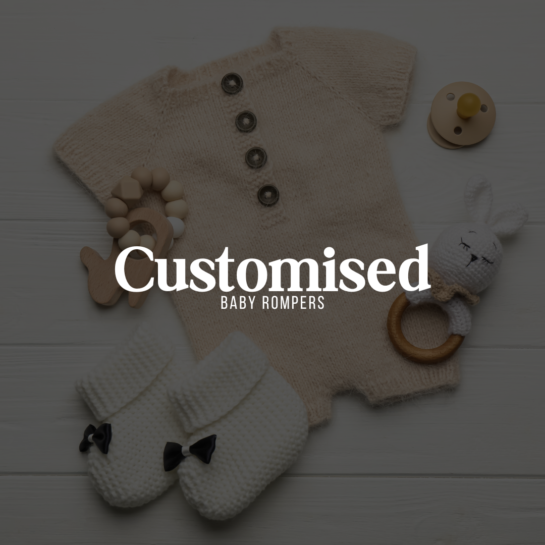 Flat lay of a knitted baby romper, white baby booties with black bows, a wooden teether, pacifier, and soft toy, with overlay text reading "Customised Baby Rompers"