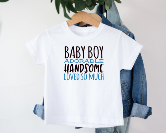 White t-shirt with text 'Baby Boy Adorable Handsome Loved So Much' on a hanger with denim jacket.