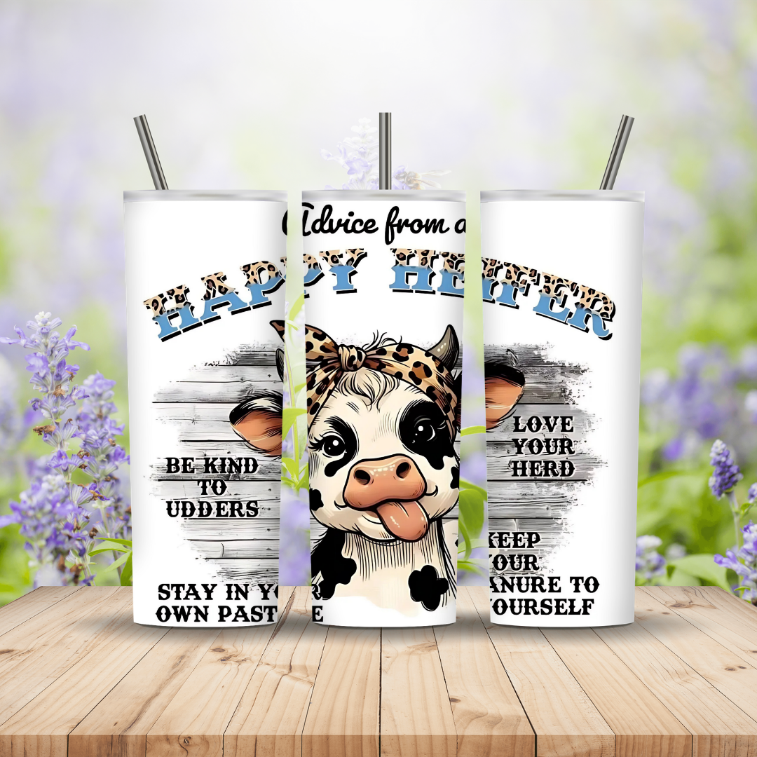 Three white tumblers with cow designs and text on a wooden surface with blurred floral background