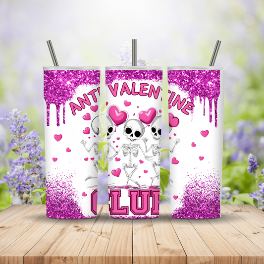 Three pink glittery tumblers with skeletons and hearts on a wooden surface with a blurred floral background.