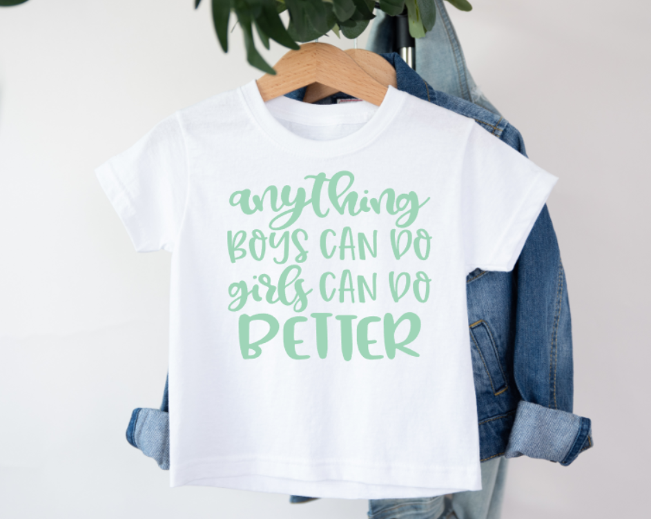White t-shirt with green text 'anything boys can do girls can do better' on a hanger with denim jacket.