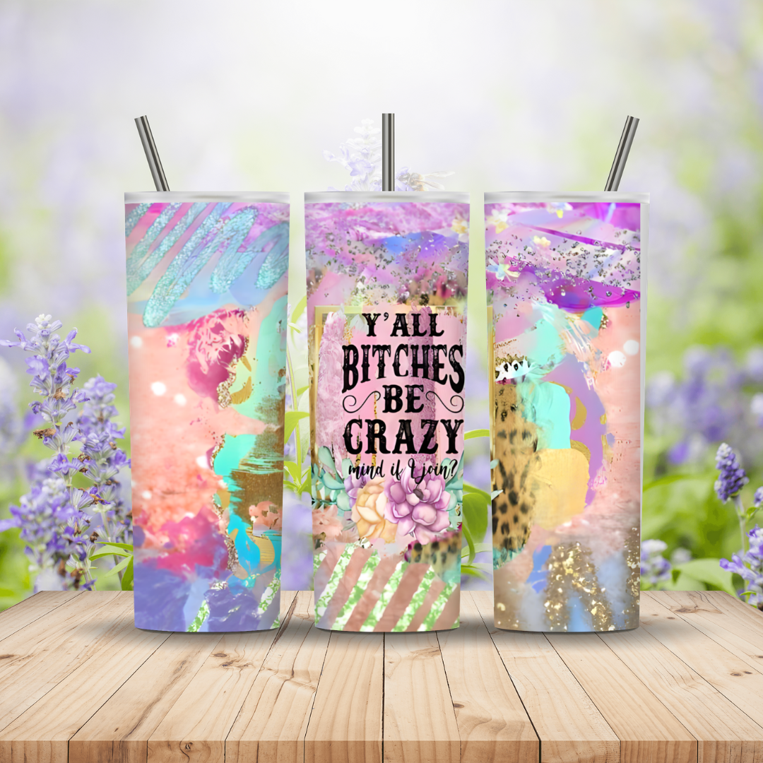 Three colorful tumblers with text and designs on a wooden surface with a floral background.