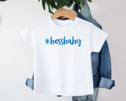 White t-shirt with '#bossbaby' text on a hanger with denim jacket