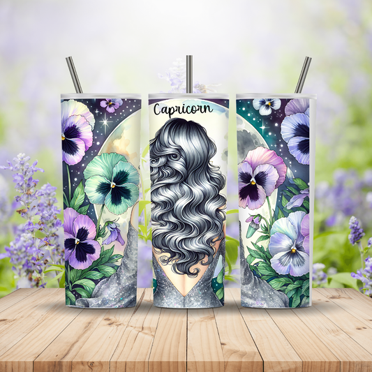 Three tumbler designs with floral and astrological themes on a wooden surface with a blurred floral background.