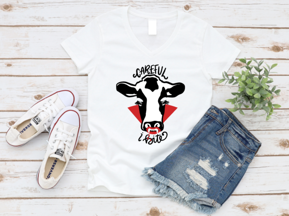 White t-shirt with cow graphic, white sneakers, and denim shorts on a wooden surface. www.missmafia.com