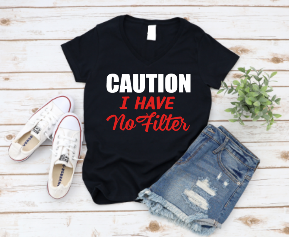 Black t-shirt with bold white and red text that reads “CAUTION I HAVE No Filter,” styled flat lay with white sneakers and ripped denim shorts on a wooden background.