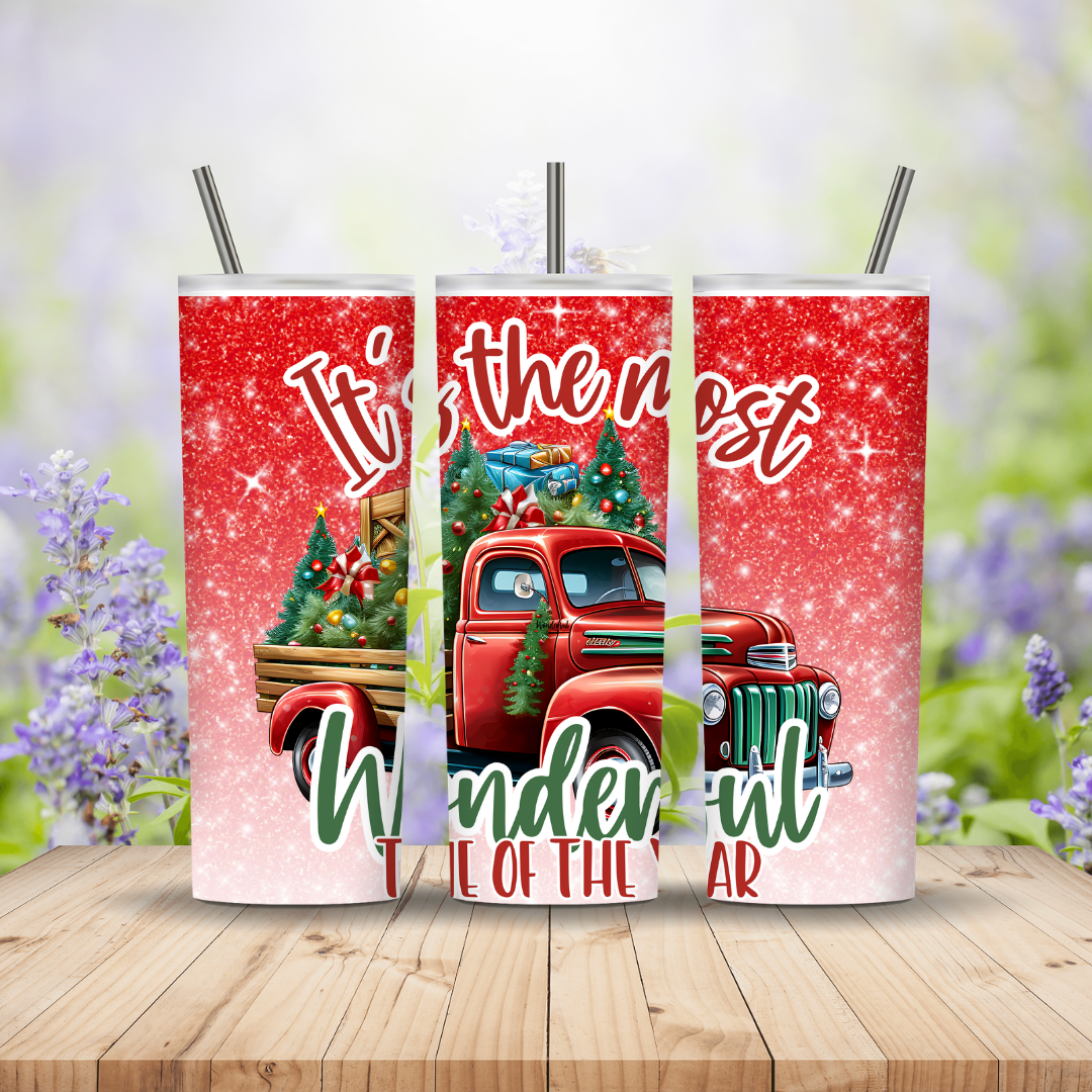 Three red tumblers with Christmas truck design on a wooden surface with blurred floral background