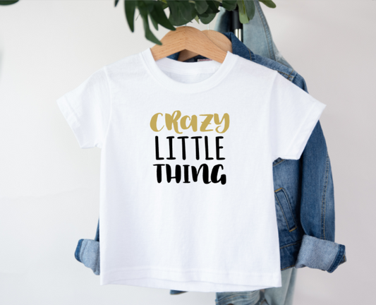White t-shirt with 'Crazy Little Thing' text on a hanger with denim jacket.