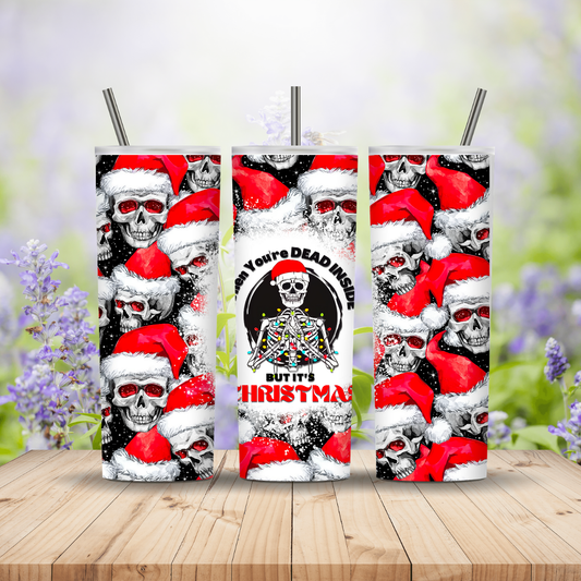 Three tumbler with skull and Santa Claus design on a wooden surface with a blurred floral background