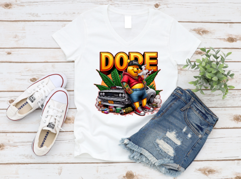 White t-shirt featuring a bold 'DOPE' graphic with a tattooed bear in streetwear, leaning against a muscle car surrounded by smoke, weed leaves, and urban details.