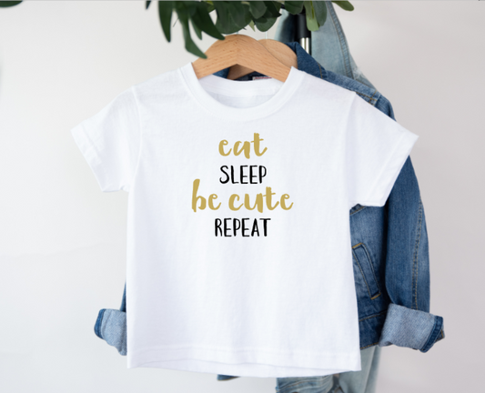 White t-shirt with 'eat sleep be cute repeat' text on a hanger with denim jacket.