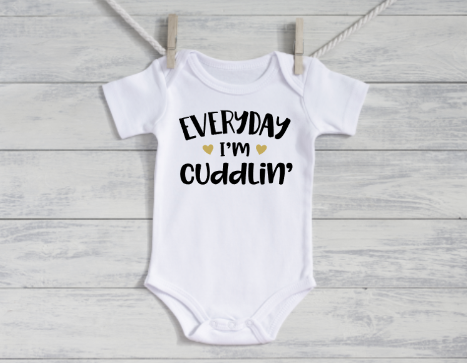 White baby onesie with text on a wooden background
