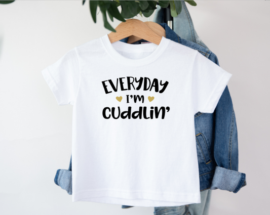 White t-shirt with 'Everyday I'm cuddlin'' text on a hanger with denim jacket.