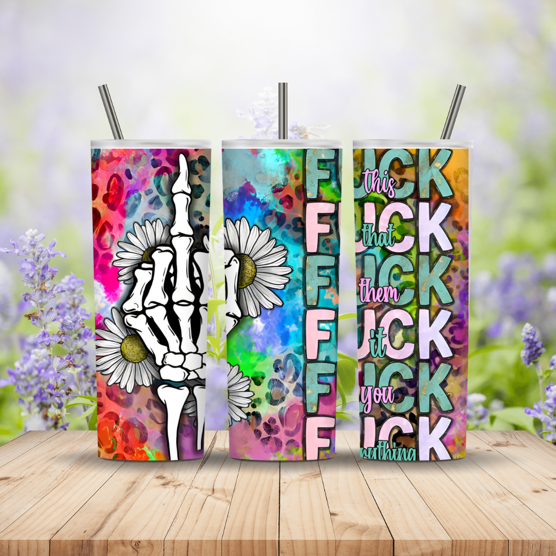 Three colorful tumblers with graphic designs and text on a wooden surface with a blurred floral background.