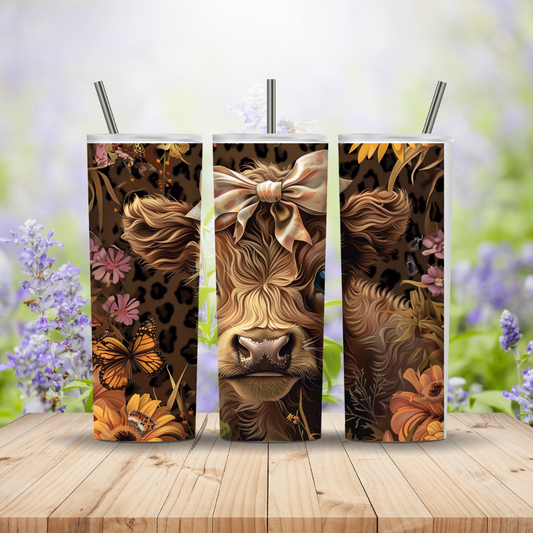 Three tumblers with a cow design on a wooden surface with a floral background