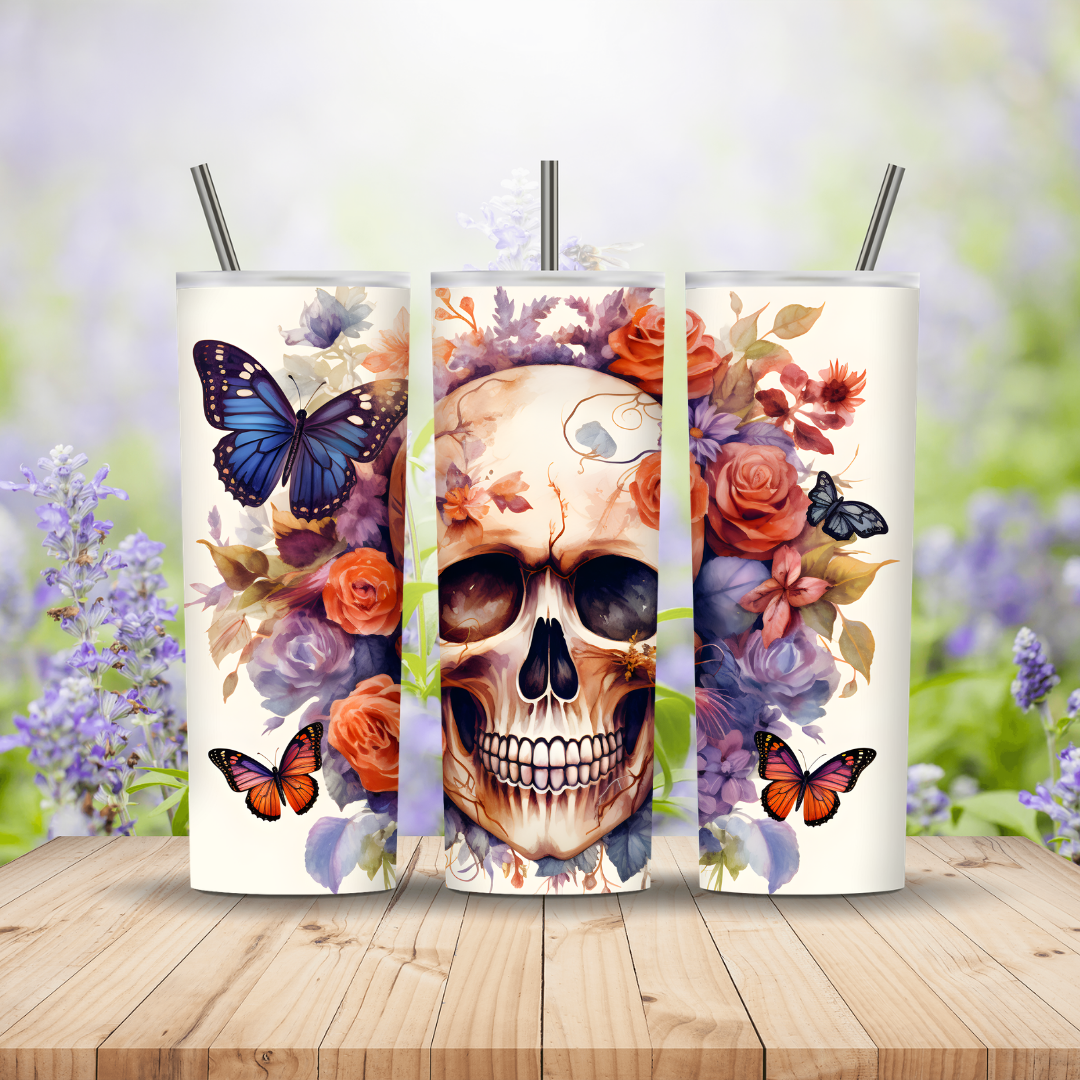 Three tumblers with skull and floral designs on a wooden surface with a blurred natural background.