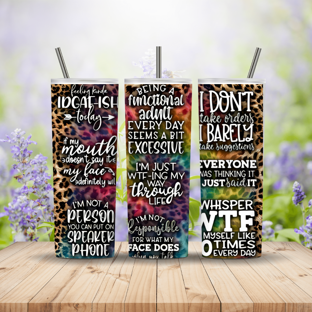 Three colorful tumblers with text designs on a wooden surface with a blurred floral background.