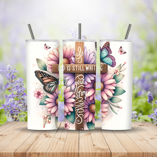 Three tumblers with floral designs and a cross, set against a blurred outdoor background. Miss Mafia