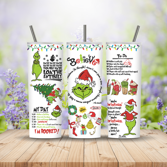 Three Christmas-themed tumblers with designs and text on a wooden surface with blurred floral background