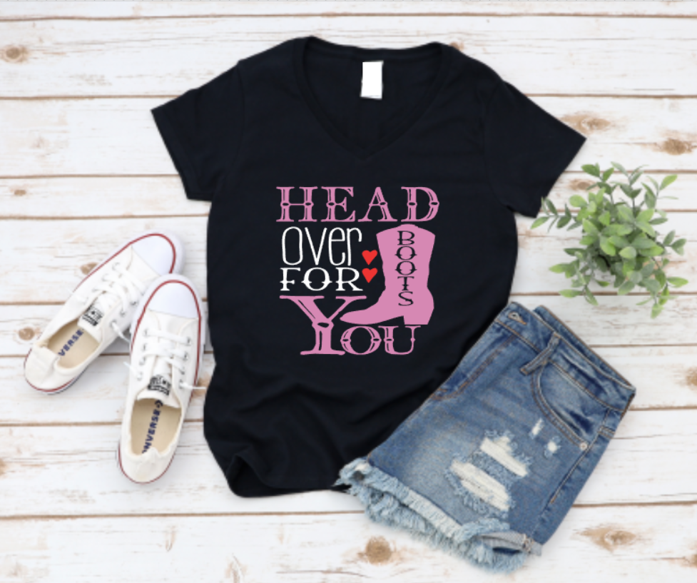 Black t-shirt with western-style typography that reads “Head Over Boots For You, on a white timber background styled with denim shorts and white converse