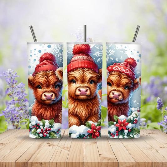 Three tumbler designs featuring Highland cows wearing red hats on a wooden surface with a blurred floral background.