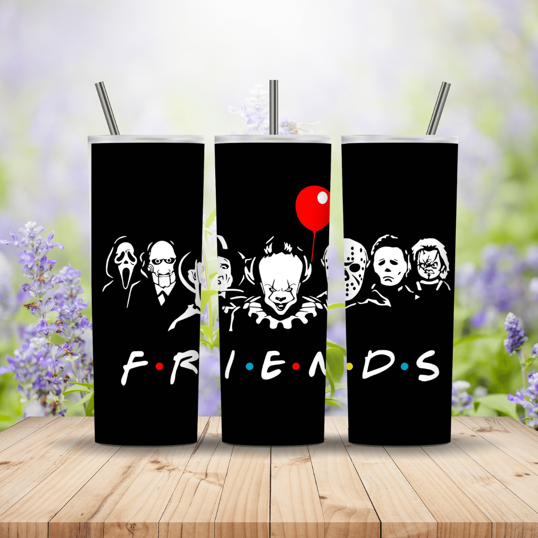 Three black tumblers with horror character faces and 'FRIENDS' text on a wooden surface with blurred floral background.