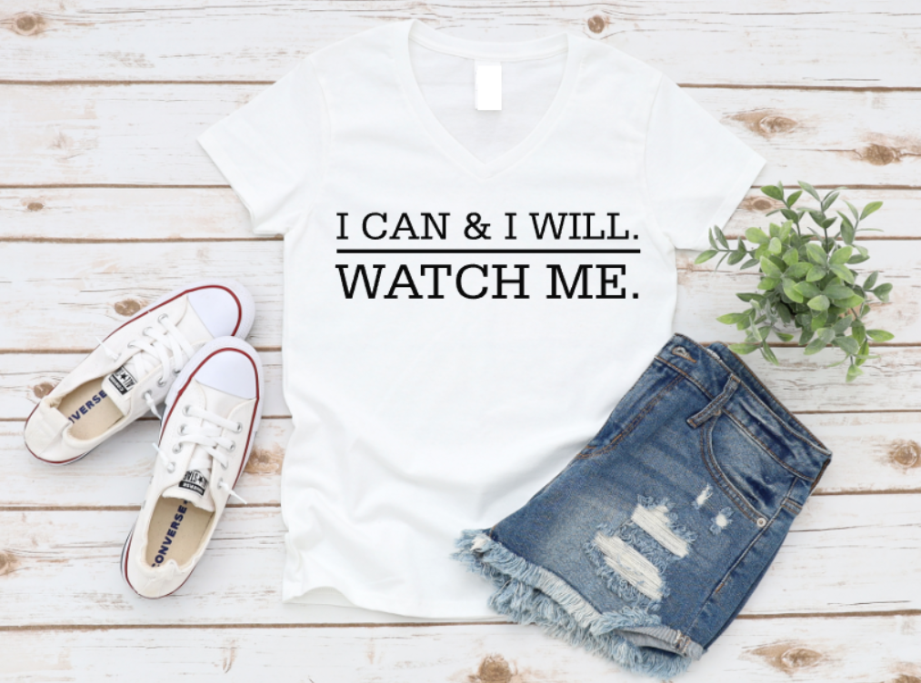 White t-shirt with motivational quote, white sneakers, and denim shorts on a wooden surface.
