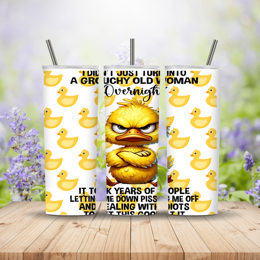 Three tumblers with a yellow duck character and text on a wooden surface with a blurred floral background.