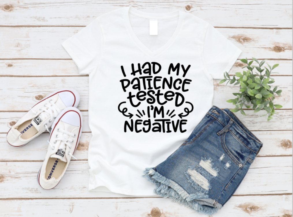 White t-shirt with text, denim shorts, and white sneakers on a wooden surface.