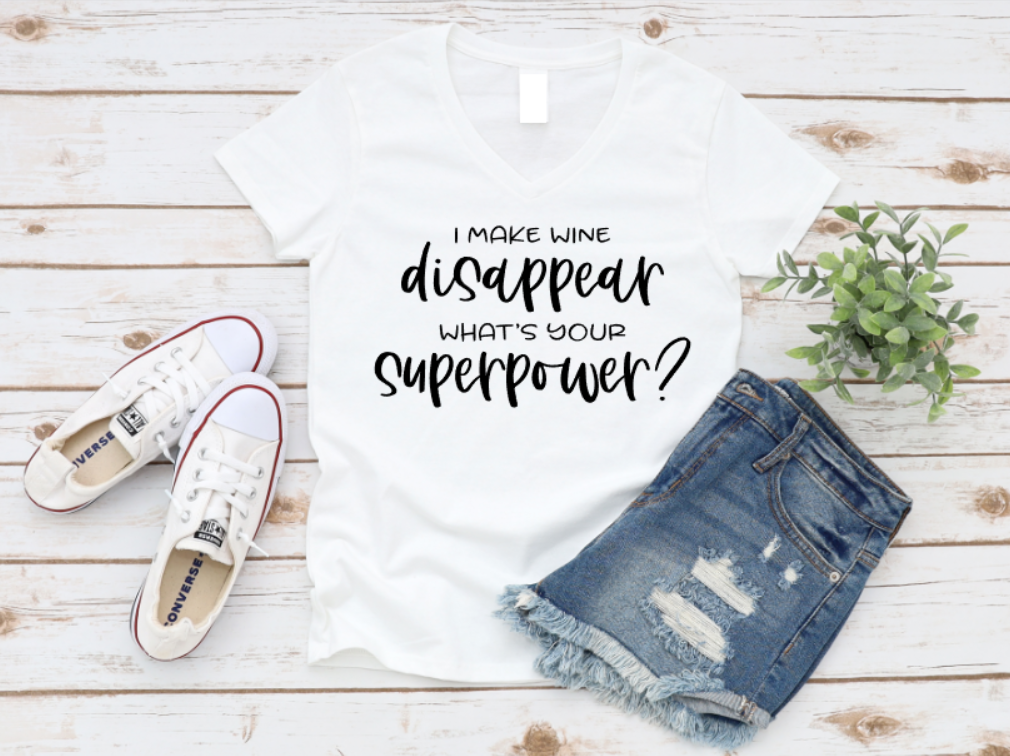 White t-shirt with humorous text, white sneakers, denim shorts, and a plant on a wooden surface.