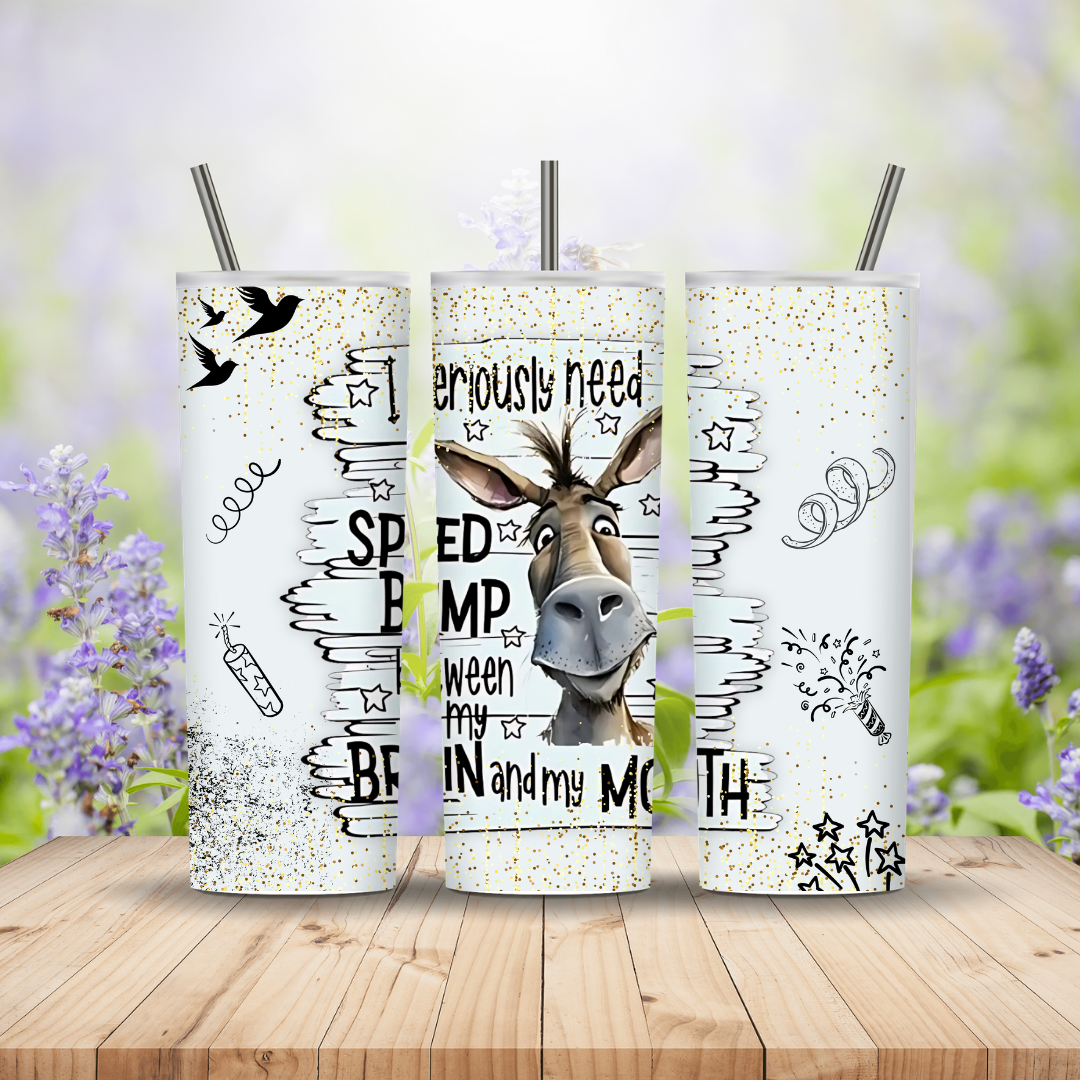 Three glittery tumblers with donkey designs and text on a wooden surface with a blurred floral background.