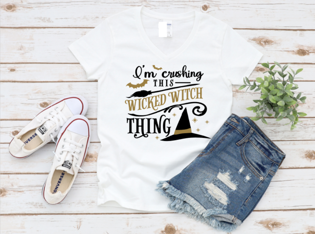 White t-shirt with 'I'm crushing this wicked witch thing' text, white sneakers, and denim shorts on a wooden surface. shop now www.missmafia.com