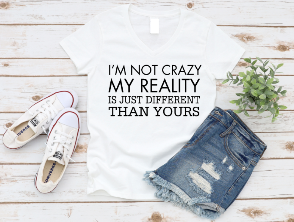 White t-shirt with text, denim shorts, and white sneakers on a wooden surface. www.missmafia.com