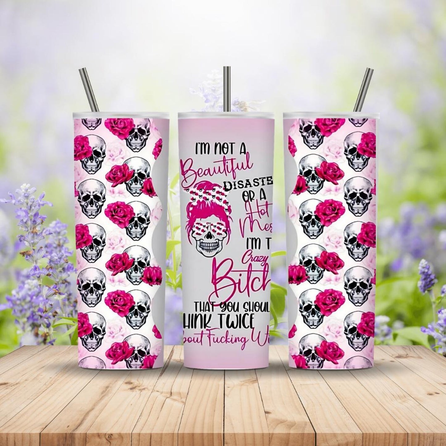 Three tumblers with skull and rose design on a wooden surface with a blurred floral background
