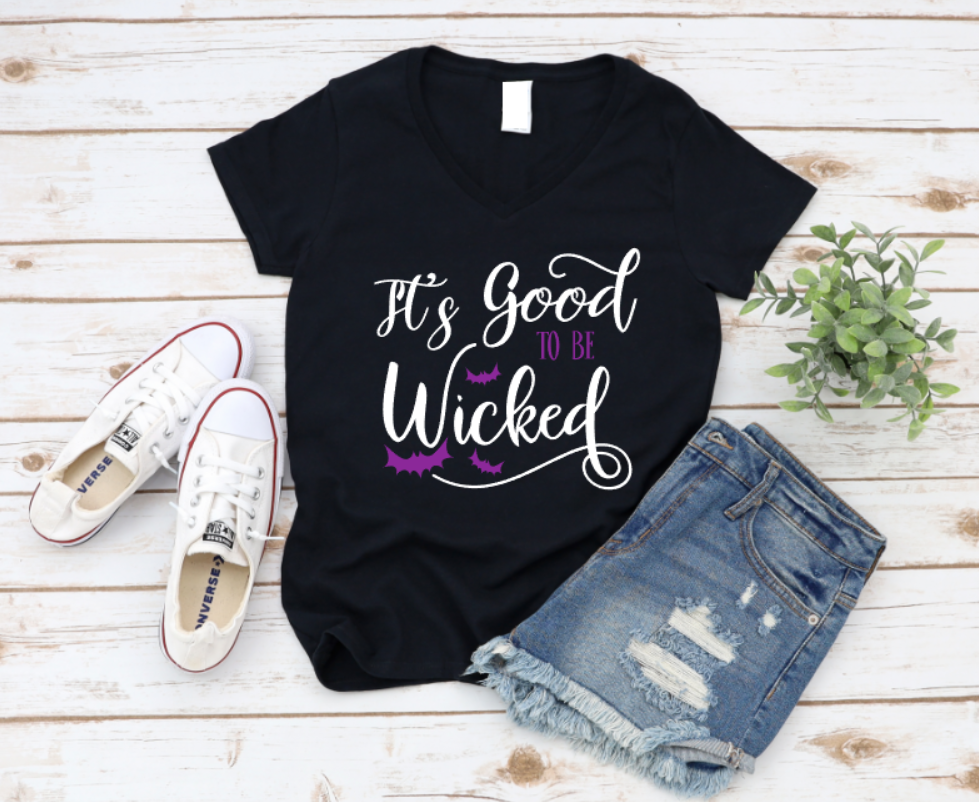 Black t-shirt with 'It's Good to be Wicked' text, paired with white sneakers and denim shorts on a wooden surface. www.missmafia.com