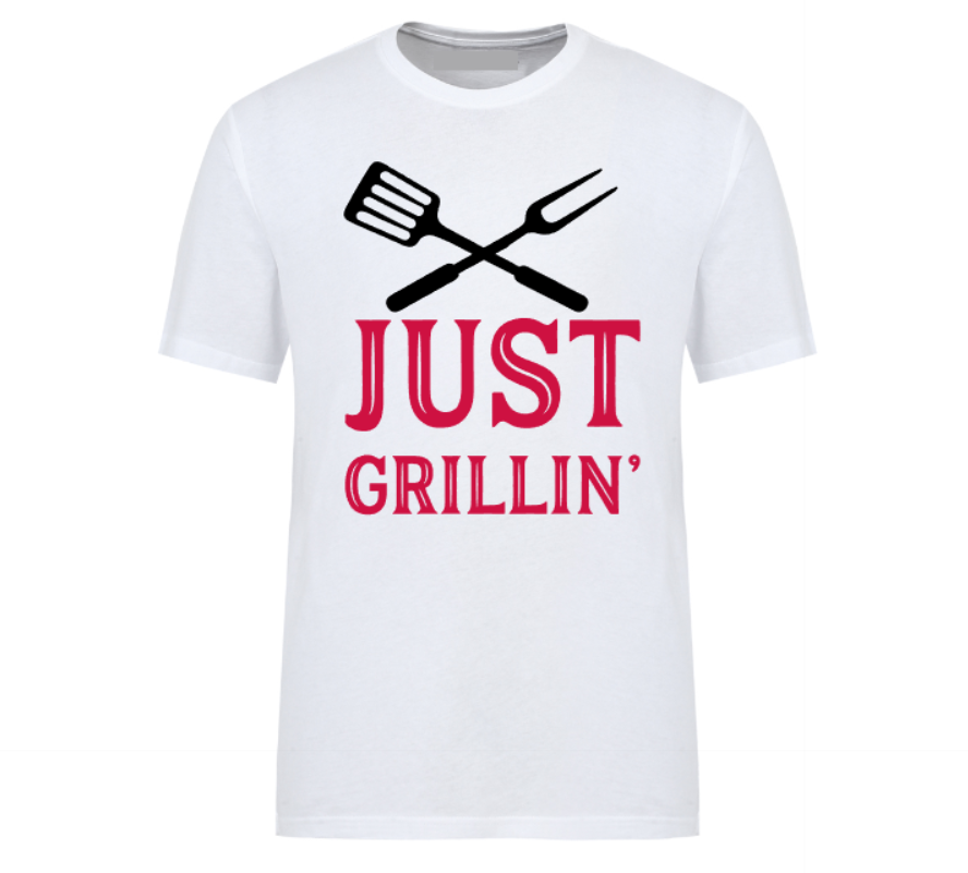 White t-shirt with bold text “Just Grillin’” featuring a grilling spatula and flame graphic, laid out flat with casual summer essentials—ideal for BBQ lovers and backyard chefs.
