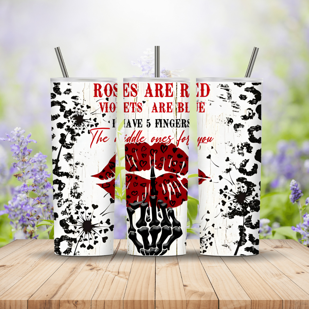 Three tumblers with floral and skeleton designs on a wooden surface with a blurred floral background.
