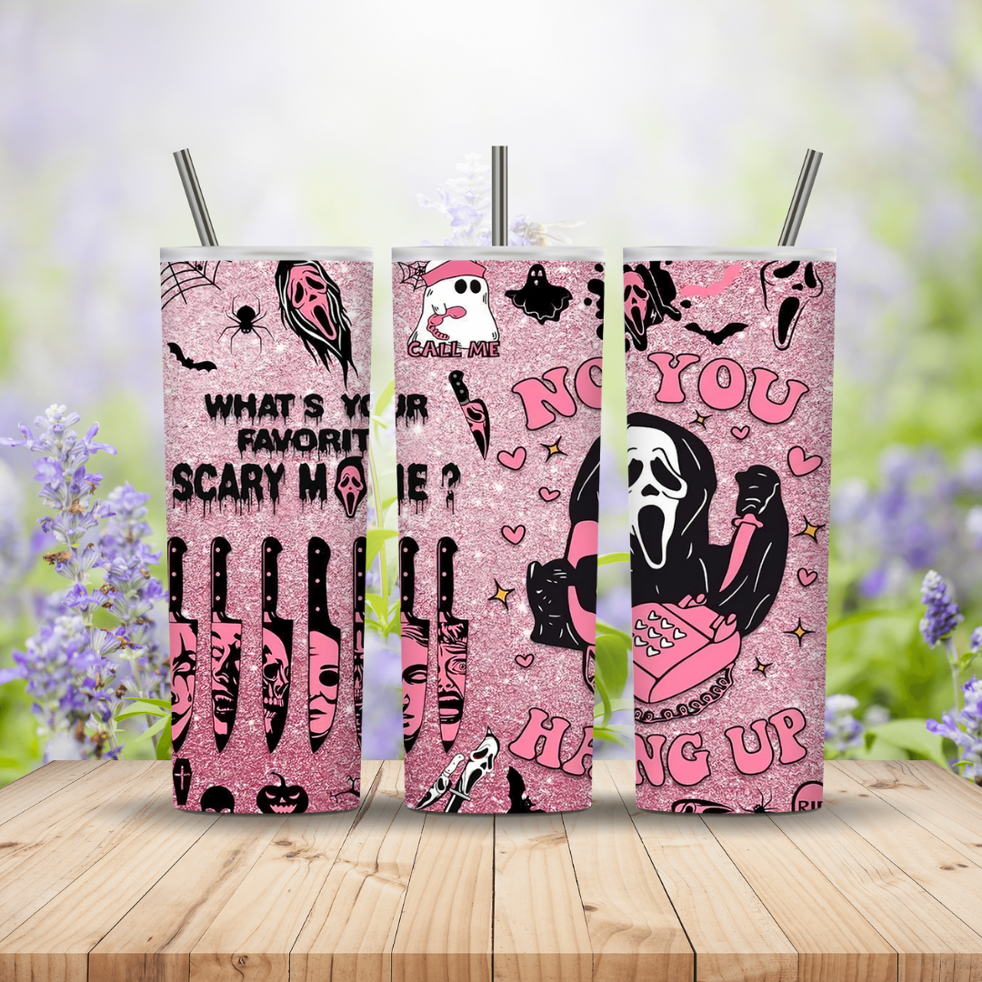 Three pink glittery tumblers with Halloween-themed designs on a wooden surface with a blurred floral background.