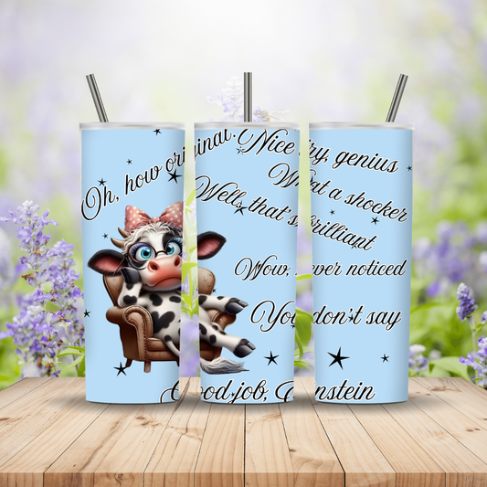 Three tumblers with a cow design and text on a wooden surface with a blurred floral background.