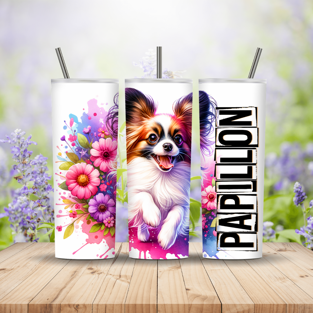 Three tumblers with a Papillon dog design and floral elements on a wooden surface with a blurred natural background.