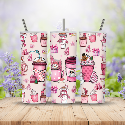 Three pink tumblers with winter-themed designs on a wooden surface with a blurred floral background.