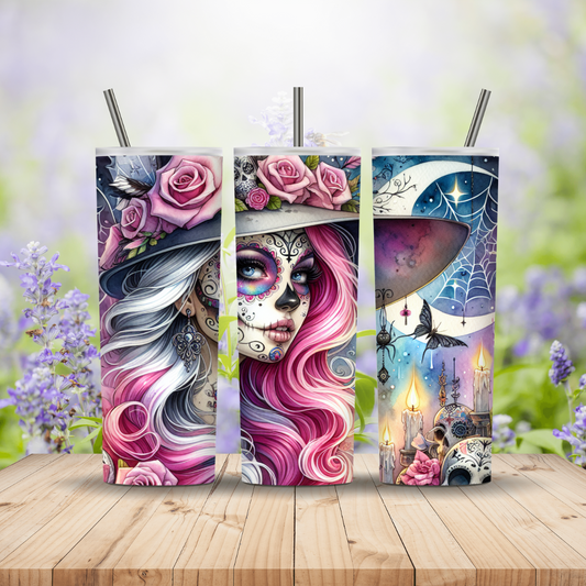 Three colorful tumblers with artistic designs on a wooden surface with a blurred floral background.