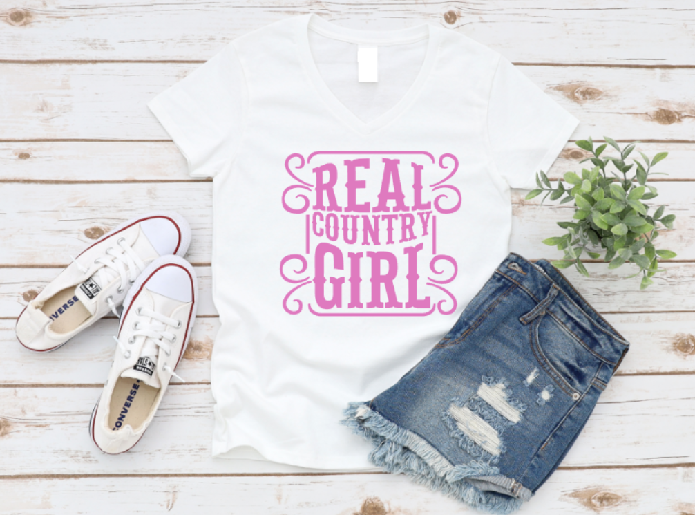 White t-shirt with 'Real Country Girl' text, denim shorts, and white sneakers on a wooden surface. www.missmafia.com