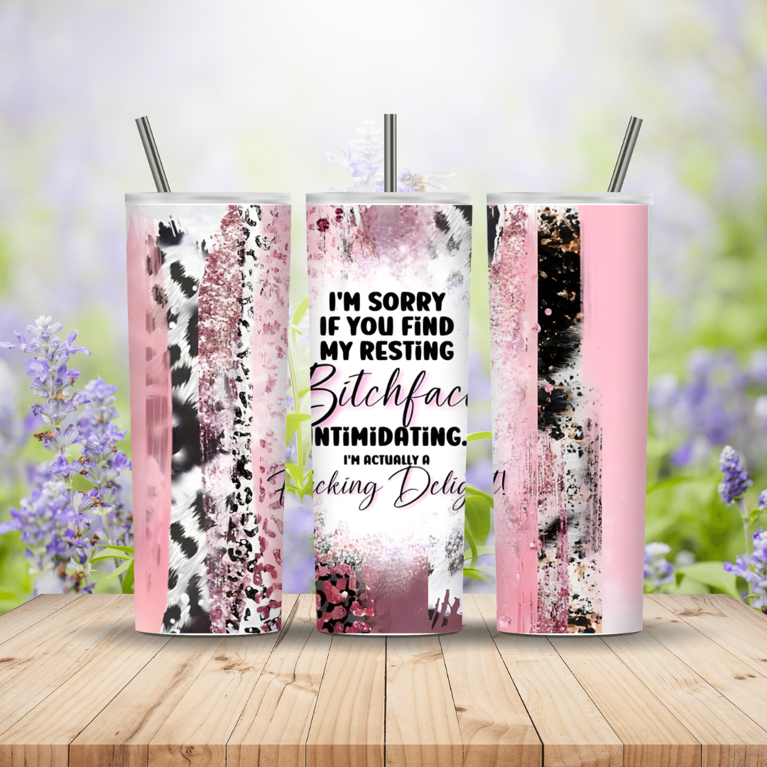 Three tumblers with pink and black designs on a wooden surface with a blurred floral background