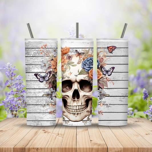 Three tumblers with skull and floral design on a wooden surface with a blurred floral background
