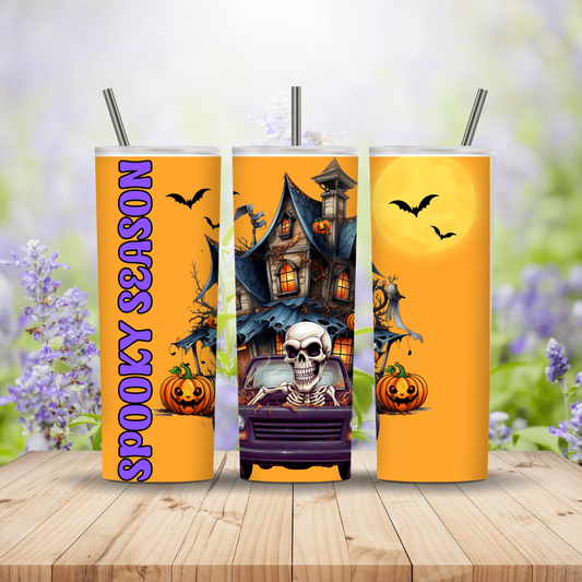 Three Halloween-themed tumblers with pumpkins, bats, and a haunted house on an orange background.