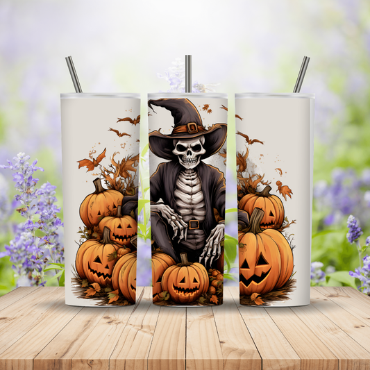 Three Halloween-themed tumblers with pumpkins and a skeleton on a wooden surface with a blurred floral background.