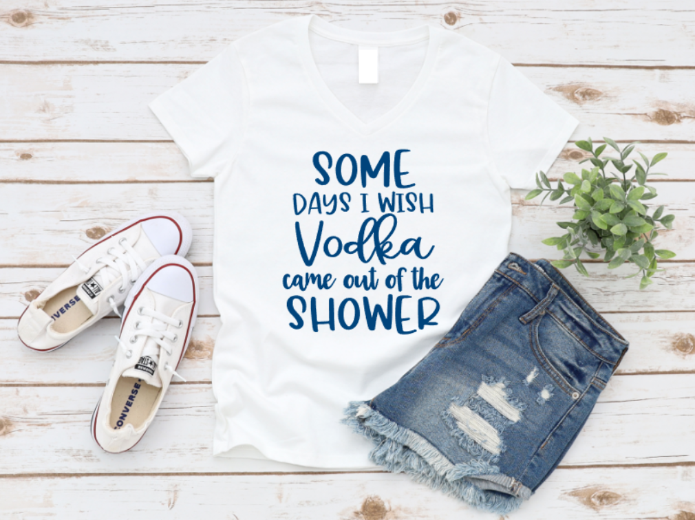 White tank top with 'Some days I wish Vodka came out of the shower' text, paired with denim shorts and white sneakers on a wooden surface. www.missmafia.com