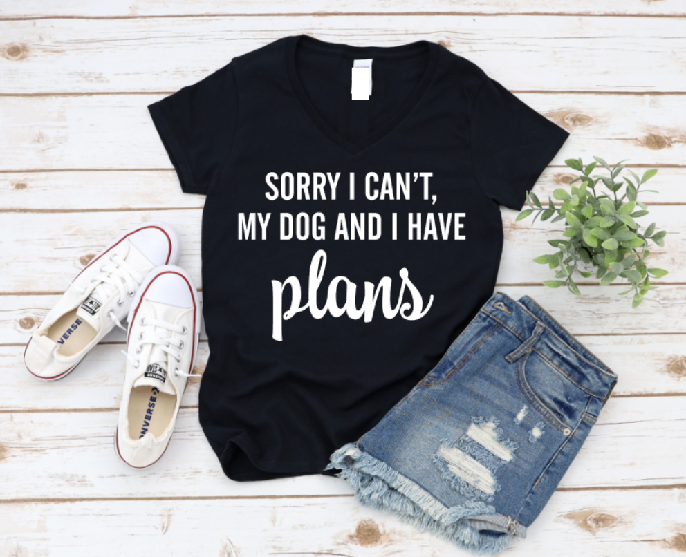 Black t-shirt with 'Sorry I can't, my dog and I have plans' text on a wooden surface with shoes and shorts. www.missmafia.com