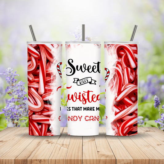 Three tumblers with candy cane design and text on a wooden surface with blurred flowers in the background